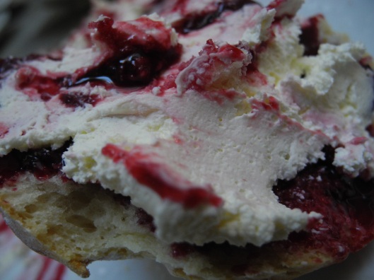 Devonshire cream on top of cherry jam on a scone